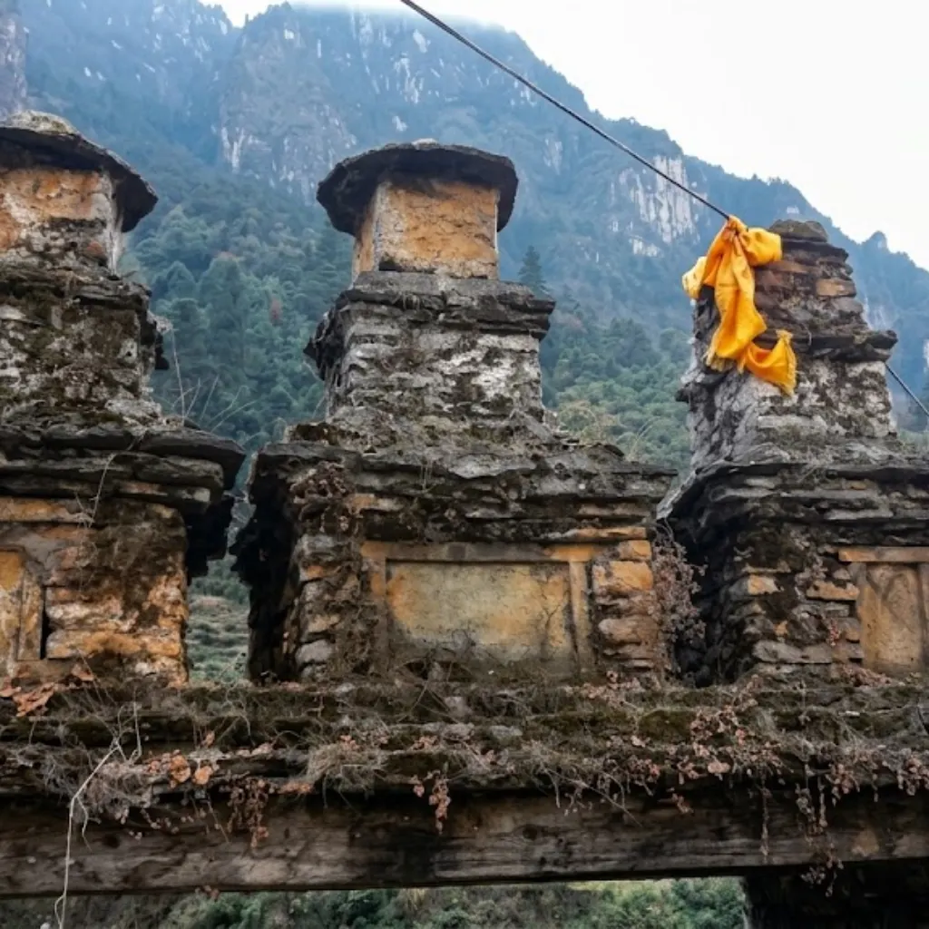 Close-up of weathered ancient stone stupas or chortens perched atop a trail gateway with a sacred yellow Buddhist prayer cloth.