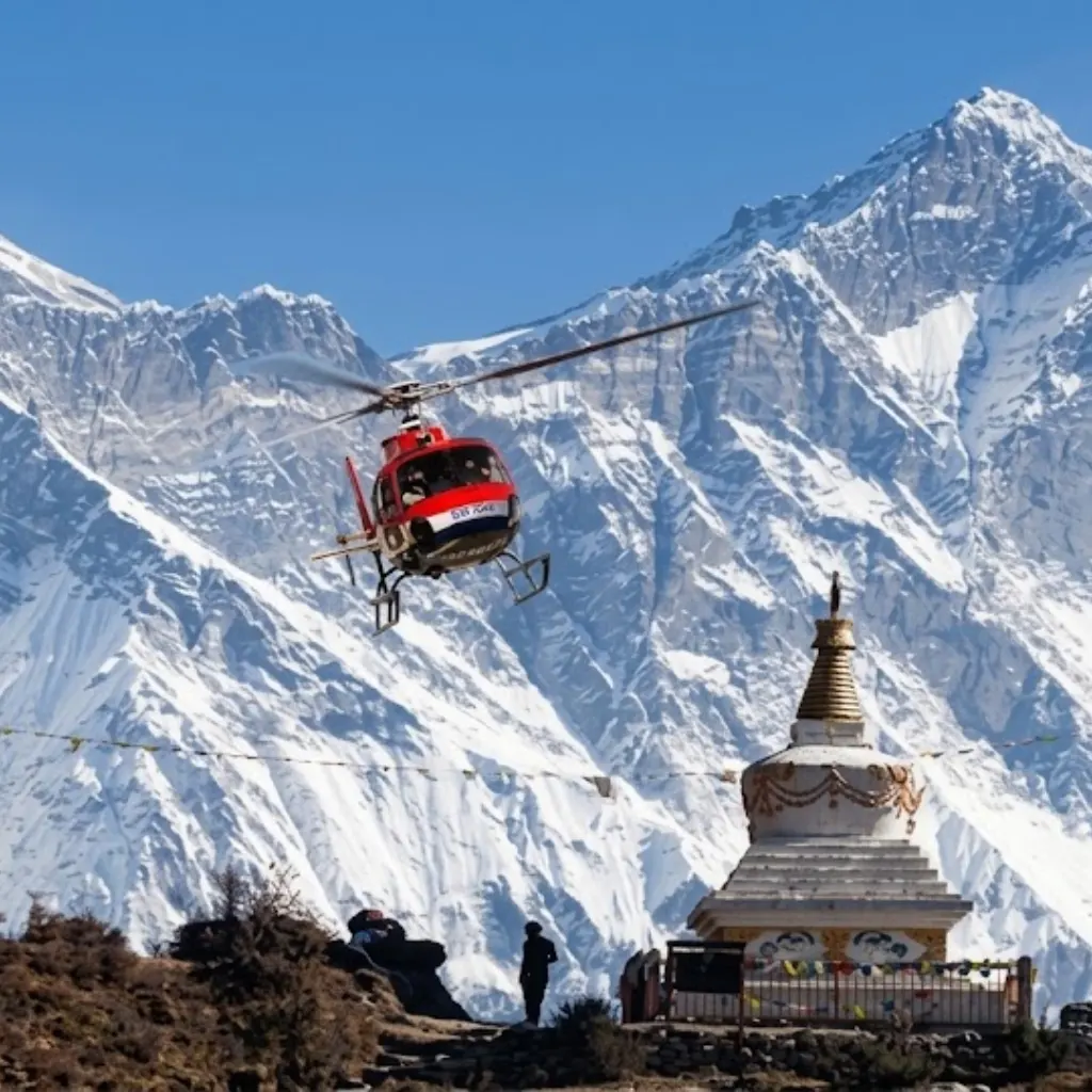 Red rescue helicopter flying past a Buddhist stupa and snow-covered Himalayan peaks in the Everest region.