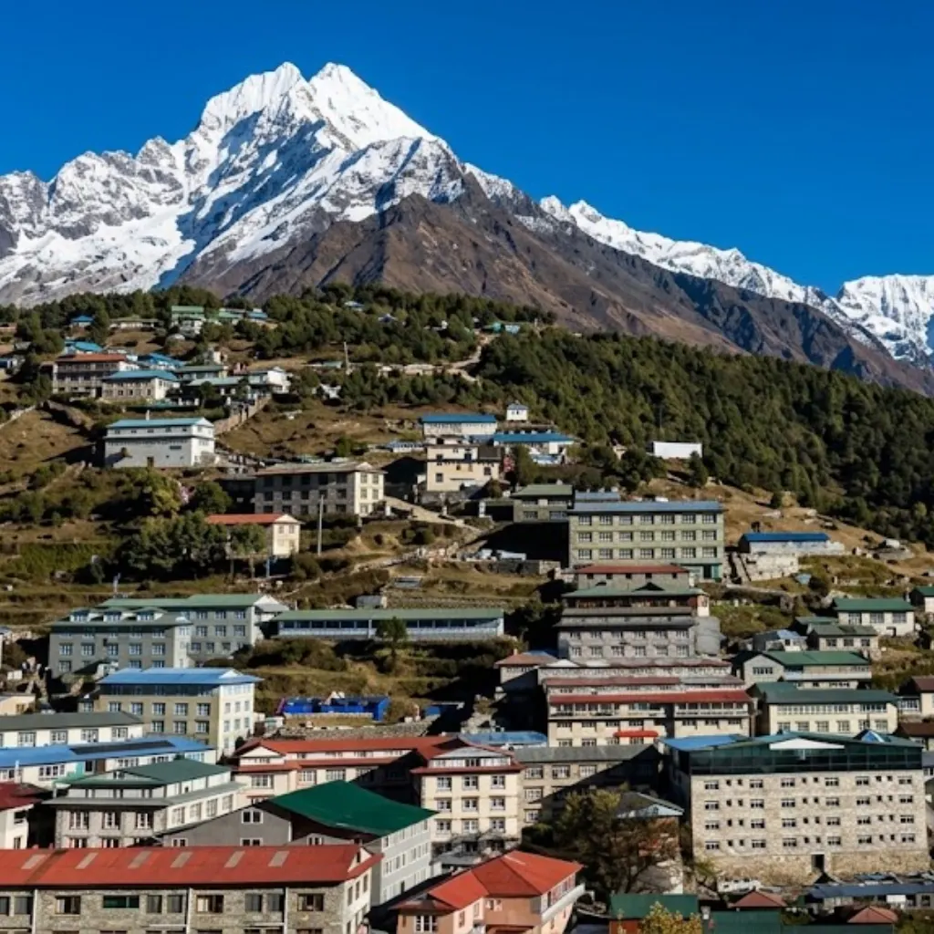 Namche Bazaar mountain village lodges stepped across hillsides beneath a snow-dusted Himalayan peak in Nepal.
