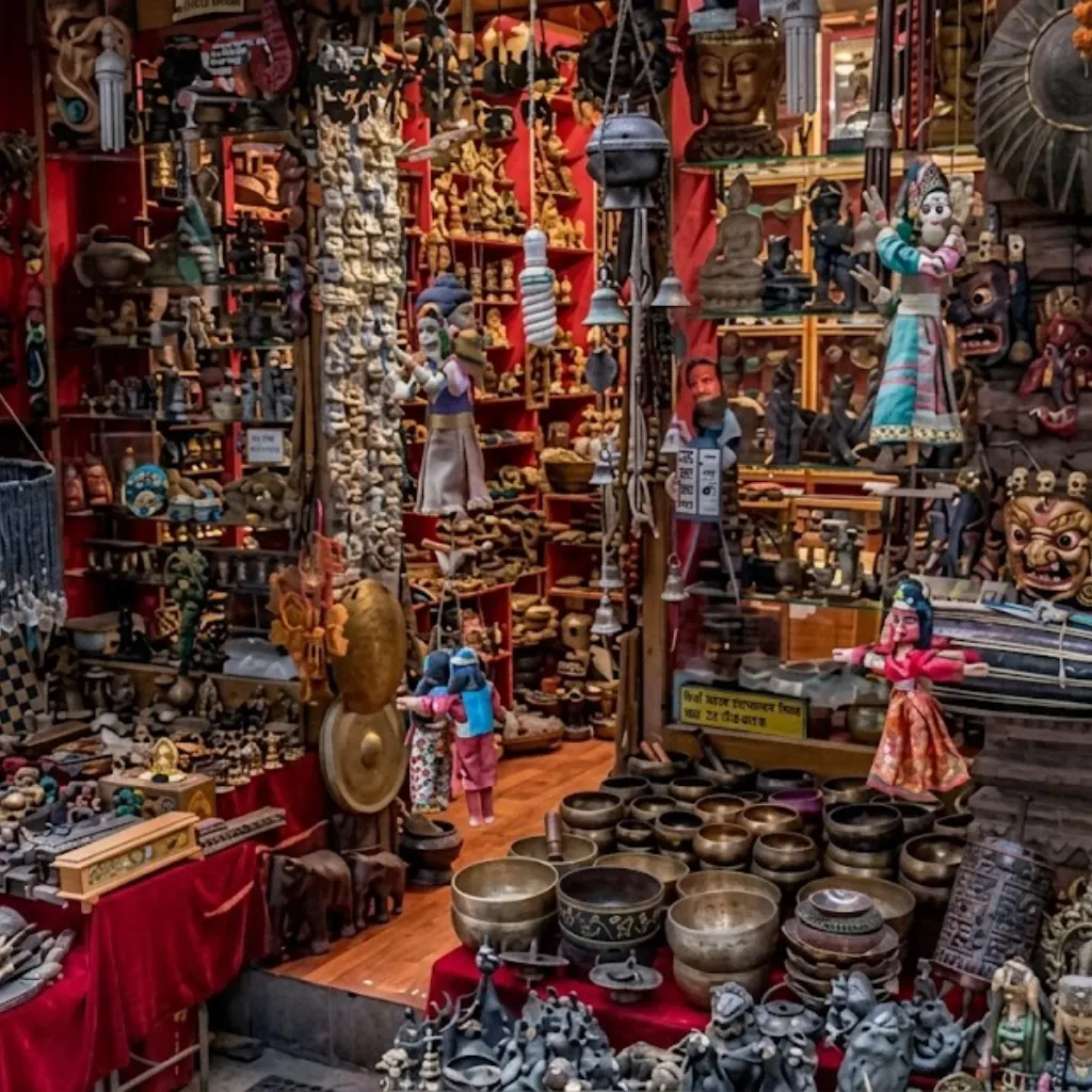 Vibrant marketplace shop in Nepal displaying traditional Tibetan singing bowls, hanging puppets, bronze statues, and carved wooden masks.