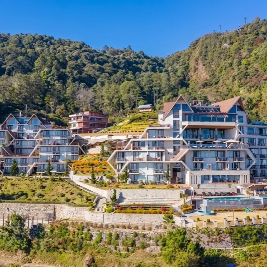 Terraced luxury mountain resort with outdoor swimming pool nestled against lush green forested hills in Nepal.
