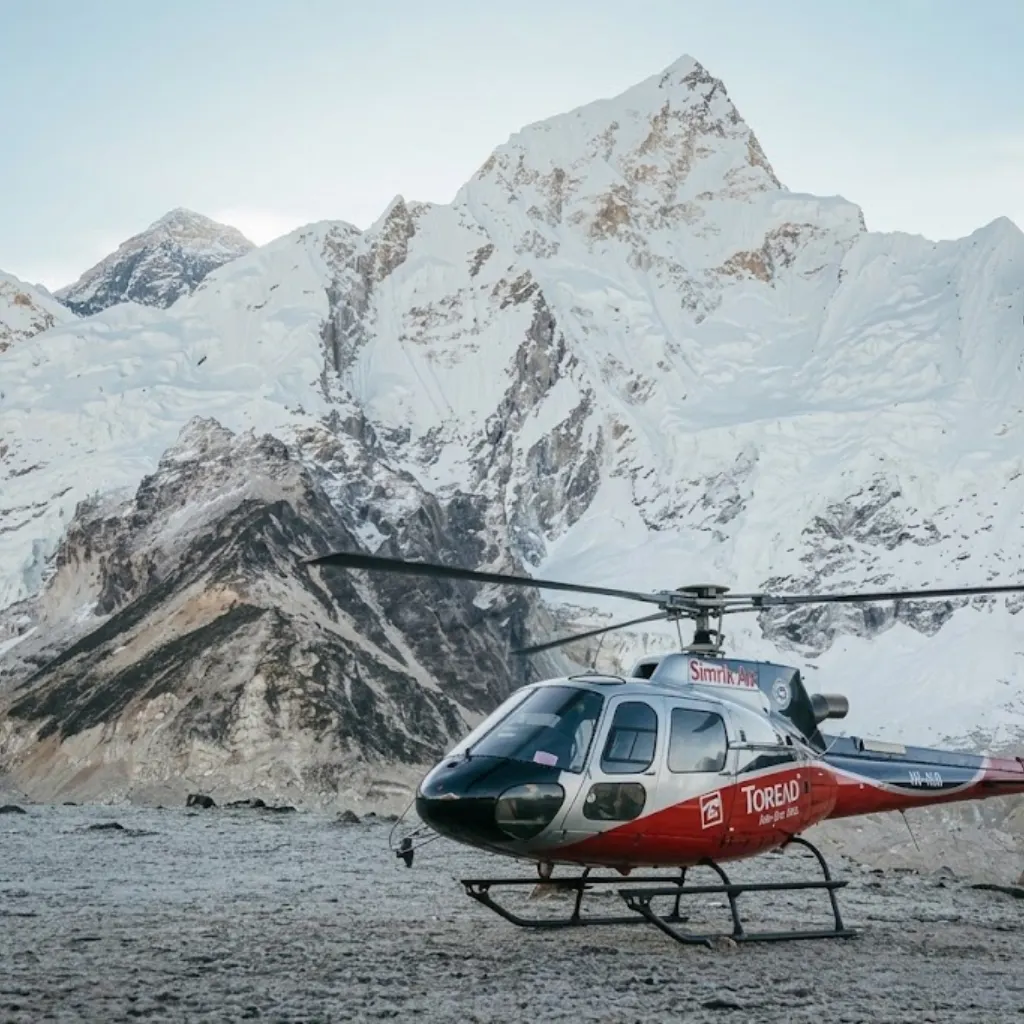 Simrik Air helicopter parked on rocky moraine ground facing the colossal snowy face of Mount Nuptse.